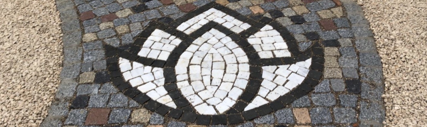 Blütenform aus Basalt und Marmor als Gestaltungselement in einem Granitpflasterweg